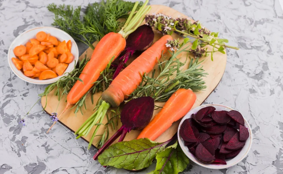Verre de jus de carotte et betterave rose orangé avec légumes frais en arrière-plan