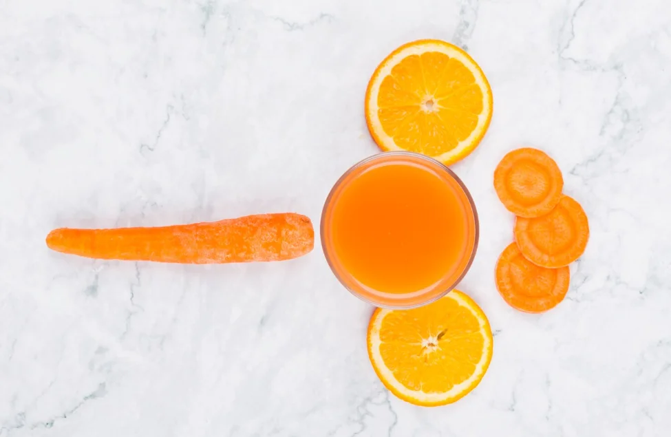 Verre de jus orange carotte avec gingembre frais et agrumes sur fond clair